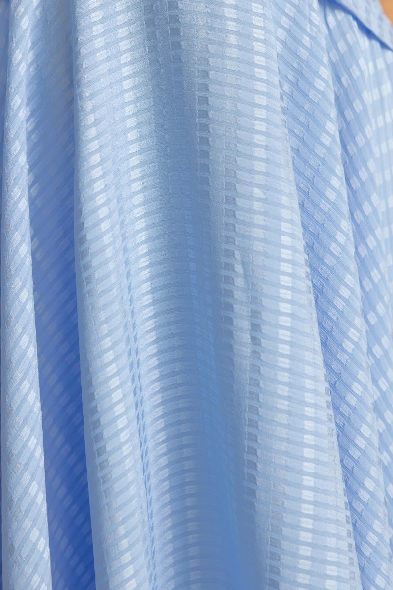 Close-up view of textured blue fabric for Angie Midi Dress, showcasing the intricate pattern and soft drape.