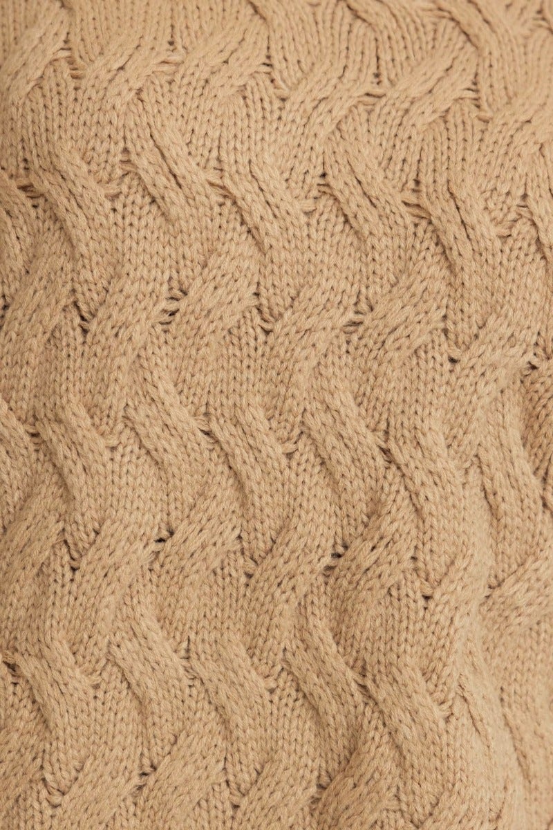 Close-up of cable knit texture in a beige jumper, showcasing the intricate pattern and warm appeal.
