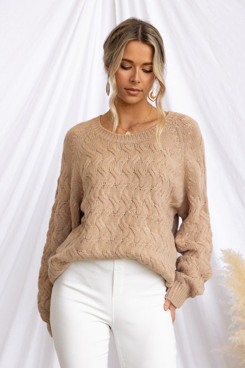 Renee Jumper in cable knit style, featuring a round neckline, relaxed fit, and soft beige color, paired with white pants.