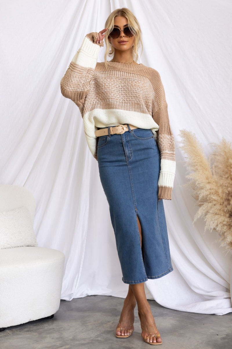 Woman wearing Evelyn Denim Midi Skirt with high waist, front slit, and cozy sweater in a stylish setting.