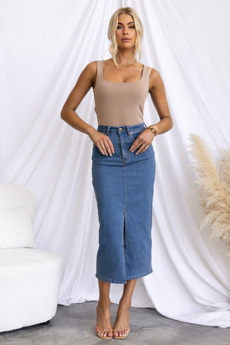 Model wearing Evelyn Denim Midi Skirt with a mid-high waist, front split, and pockets, styled with a beige top.