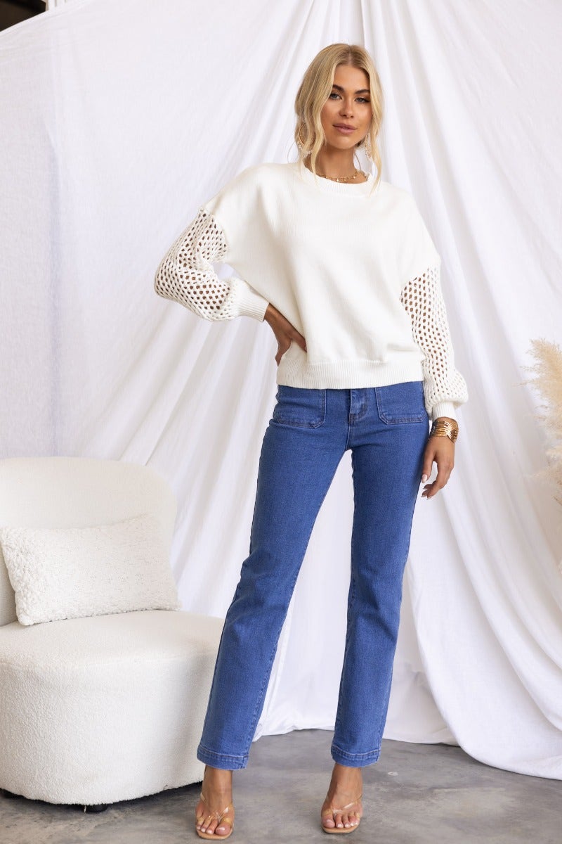 Verny jumper featuring ribbed knit and open weave sleeves, styled with blue jeans and a stylish pose.
