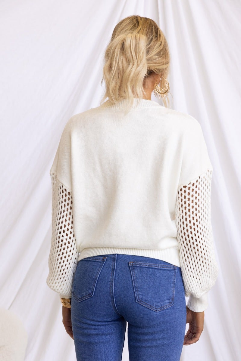 Back view of Verny Jumper, featuring ribbed knit and open weave sleeves, styled with blue jeans.