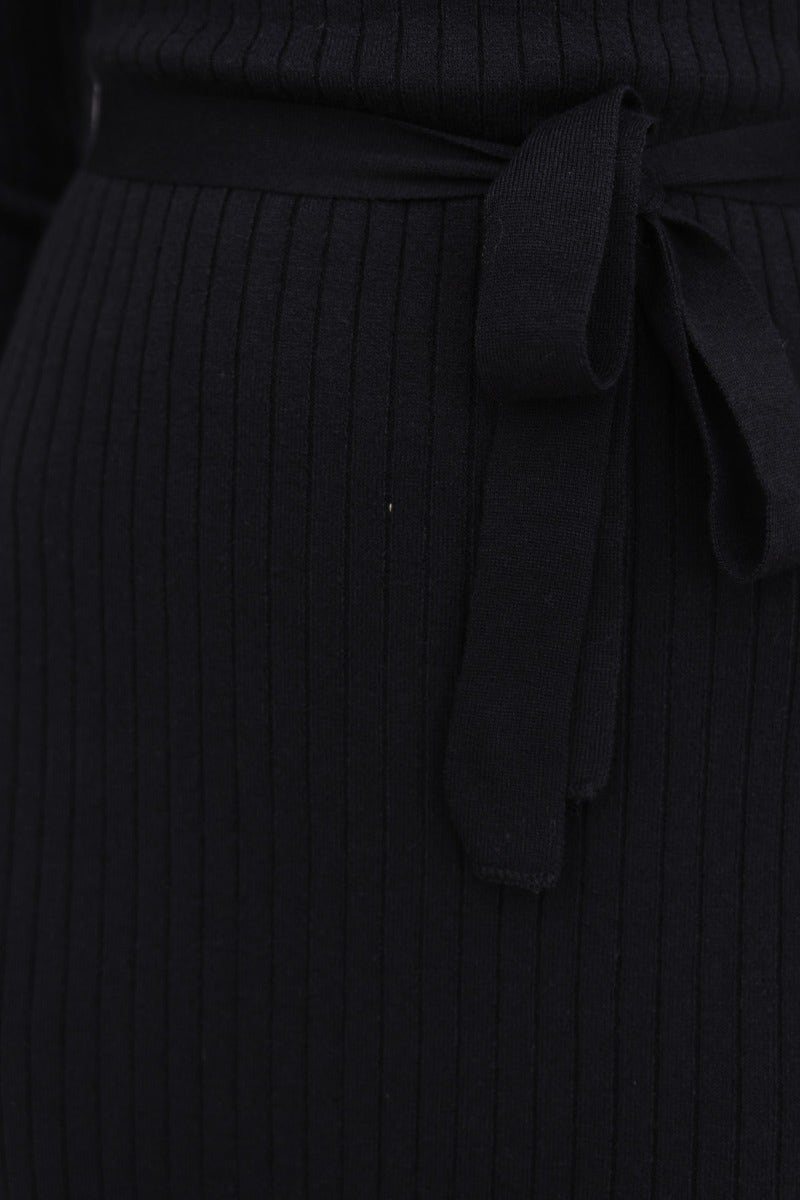 Close-up of black ribbed knit dress featuring a removable fabric belt tied at the waist.