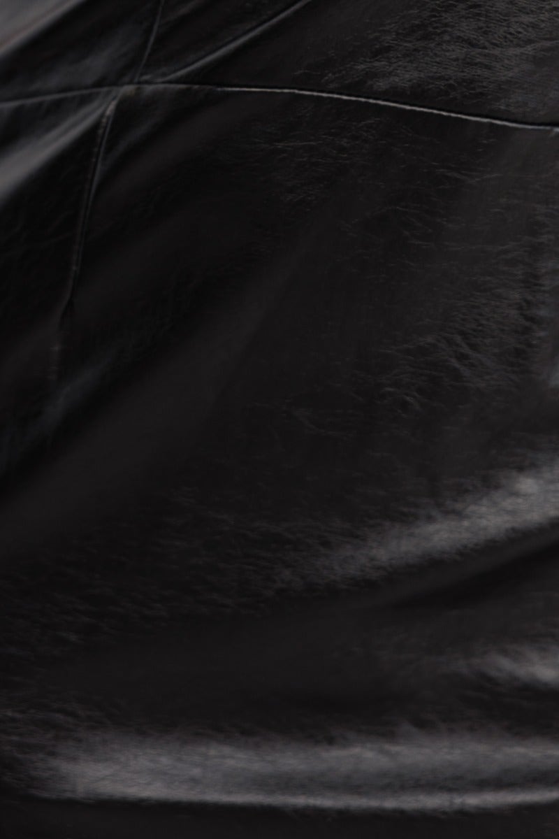 Close-up of black faux leather texture, highlighting the sleek finish of the Neo Midi Dress, showcasing its modern design.