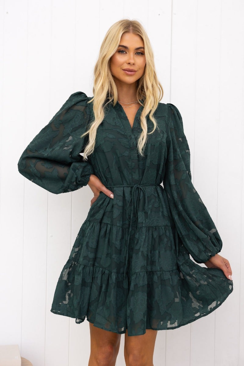 Model wearing a green embossed print Halston dress with button-up front and elastic sleeve cuffs.