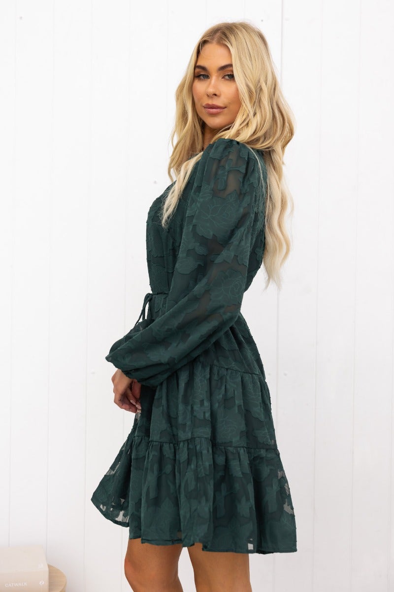 Model in a green embossed Halston dress with button-up front and elastic sleeve cuffs.
