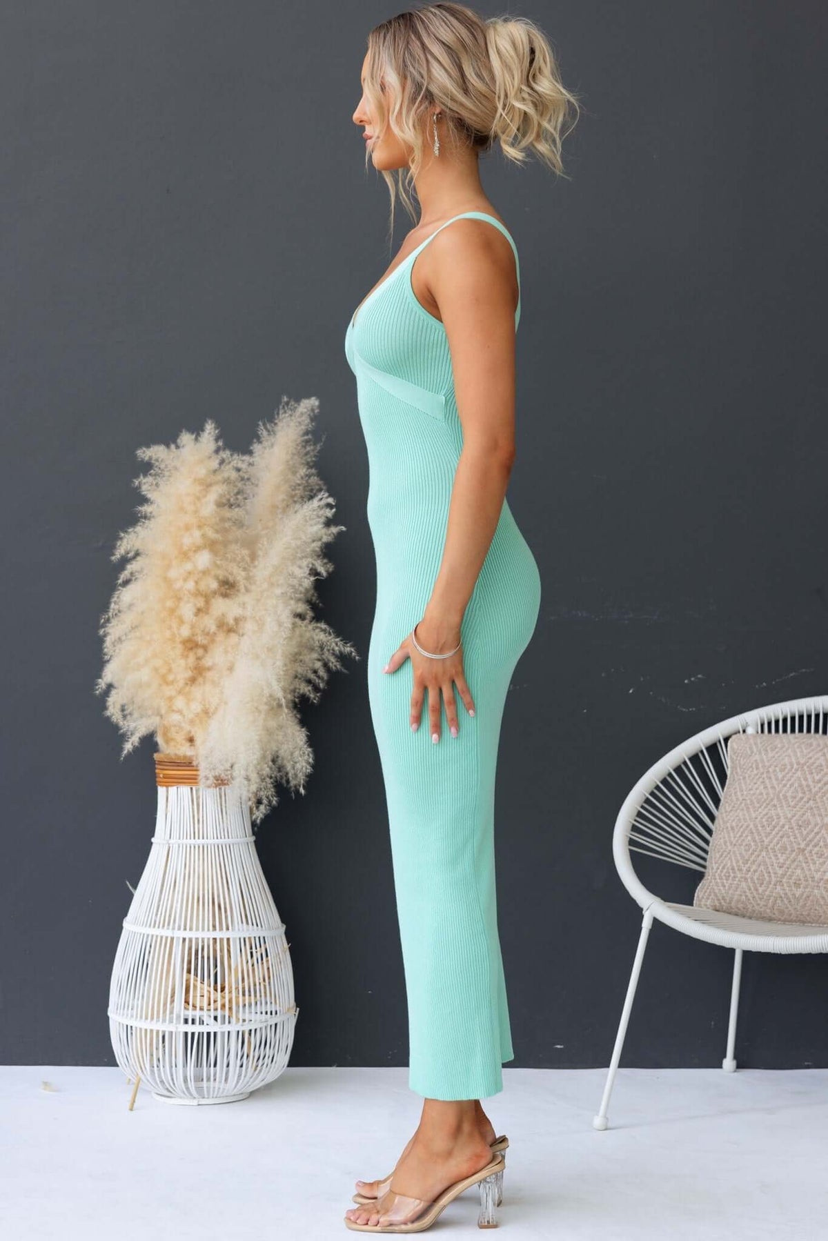 Side view of a woman in a mint green Calluna Maxi Dress with a V-neckline and ribbed knit design.