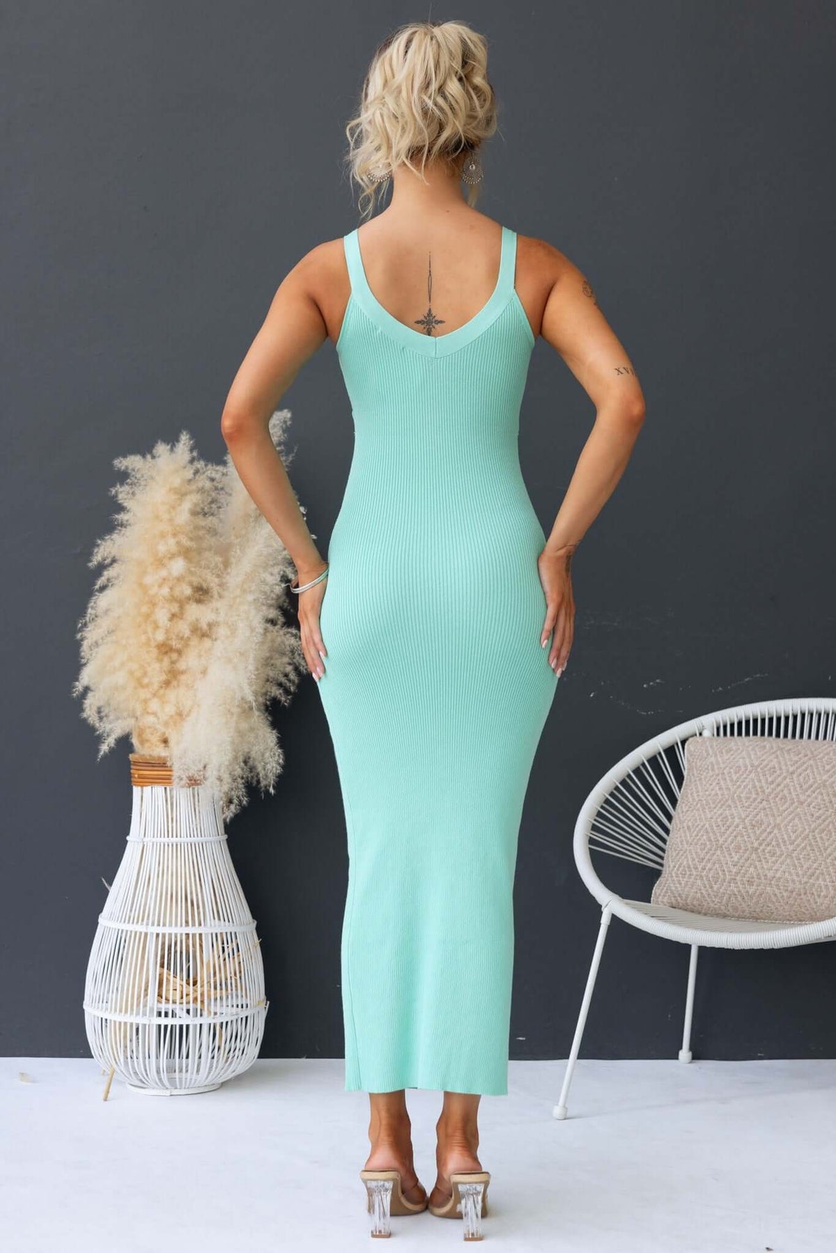 Back view of a woman in a mint green Calluna maxi dress with V-neckline and ribbed knit material.
