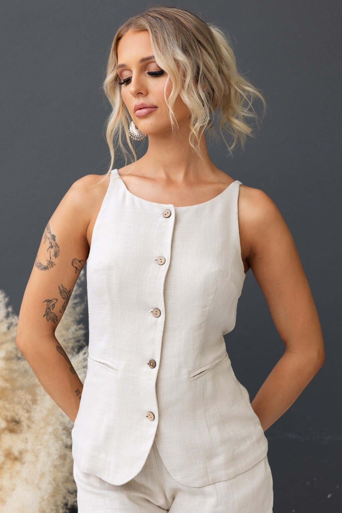 Woman wearing the Shelton Top, a stylish button-up linen blend top in light beige, showcasing a chic and modern design.