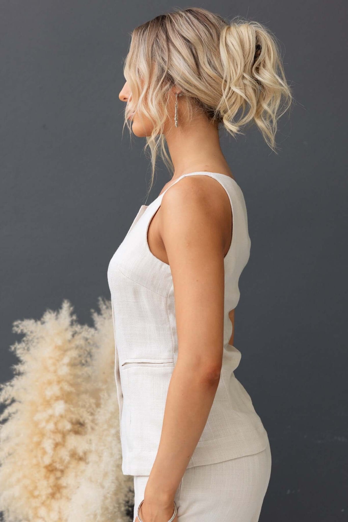 Side view of the Shelton Top, a sleeveless button-up top with faux pockets, styled elegantly against a neutral backdrop.