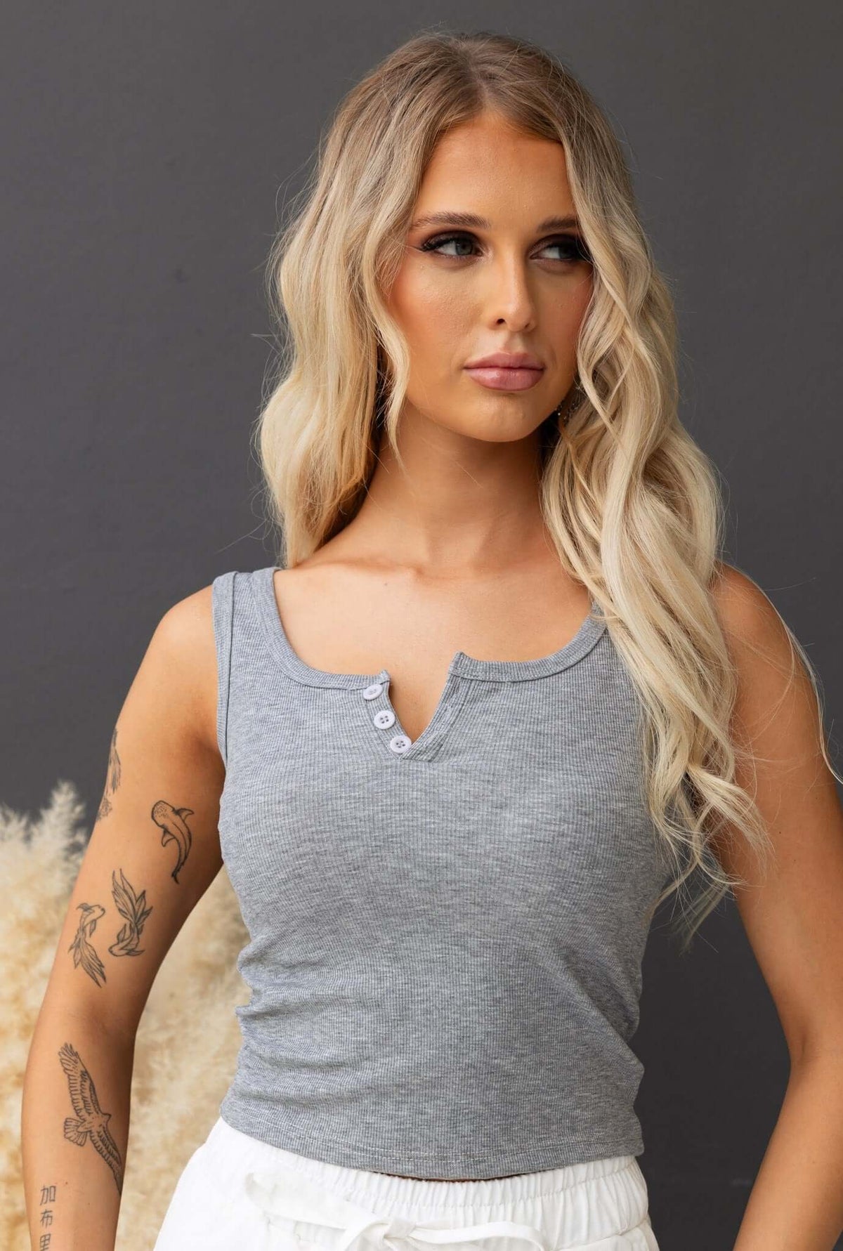 Grey ribbed top with button detail at bust, featuring a comfortable, stretchy fit and model wearing size 8/S.