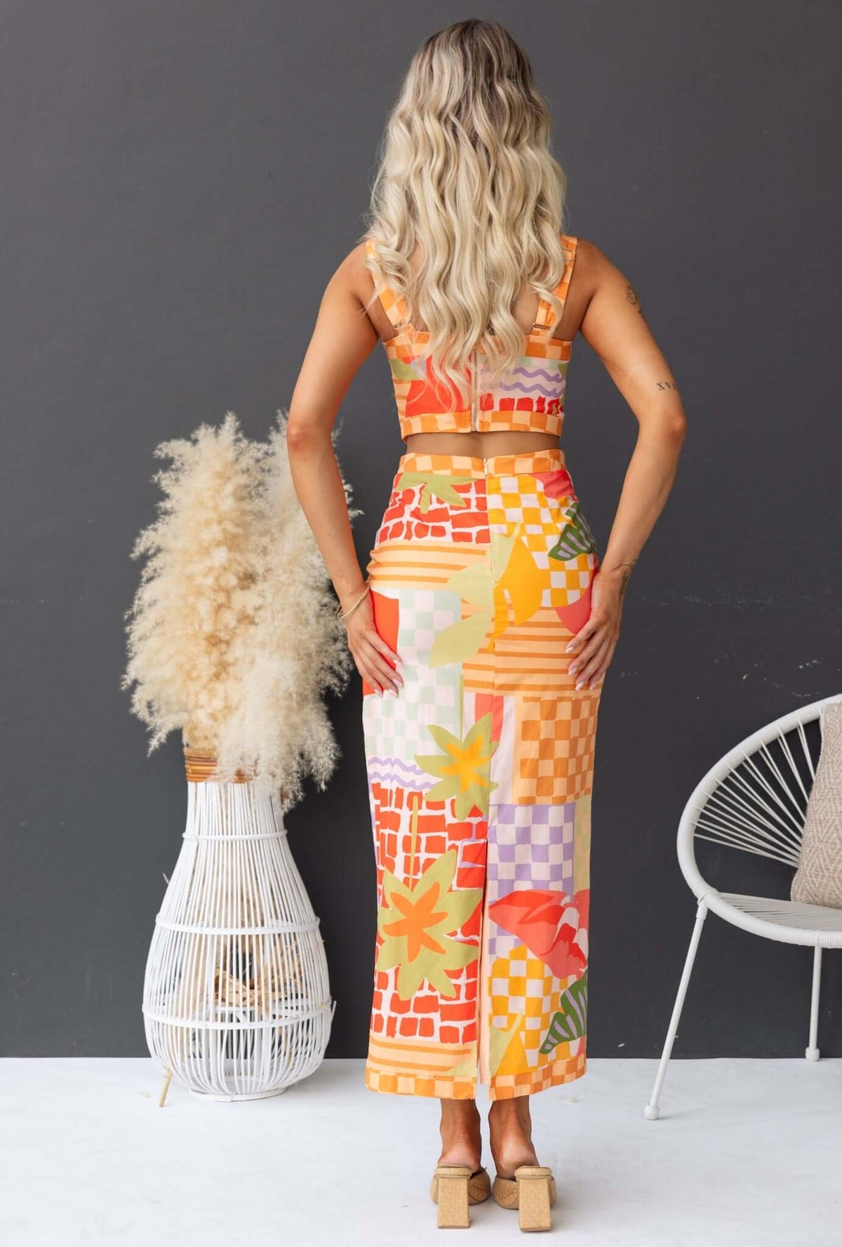 Back view of a model wearing a colorful Paltrow Set with a fitted top and non-stretch maxi skirt in a bright garden design.
