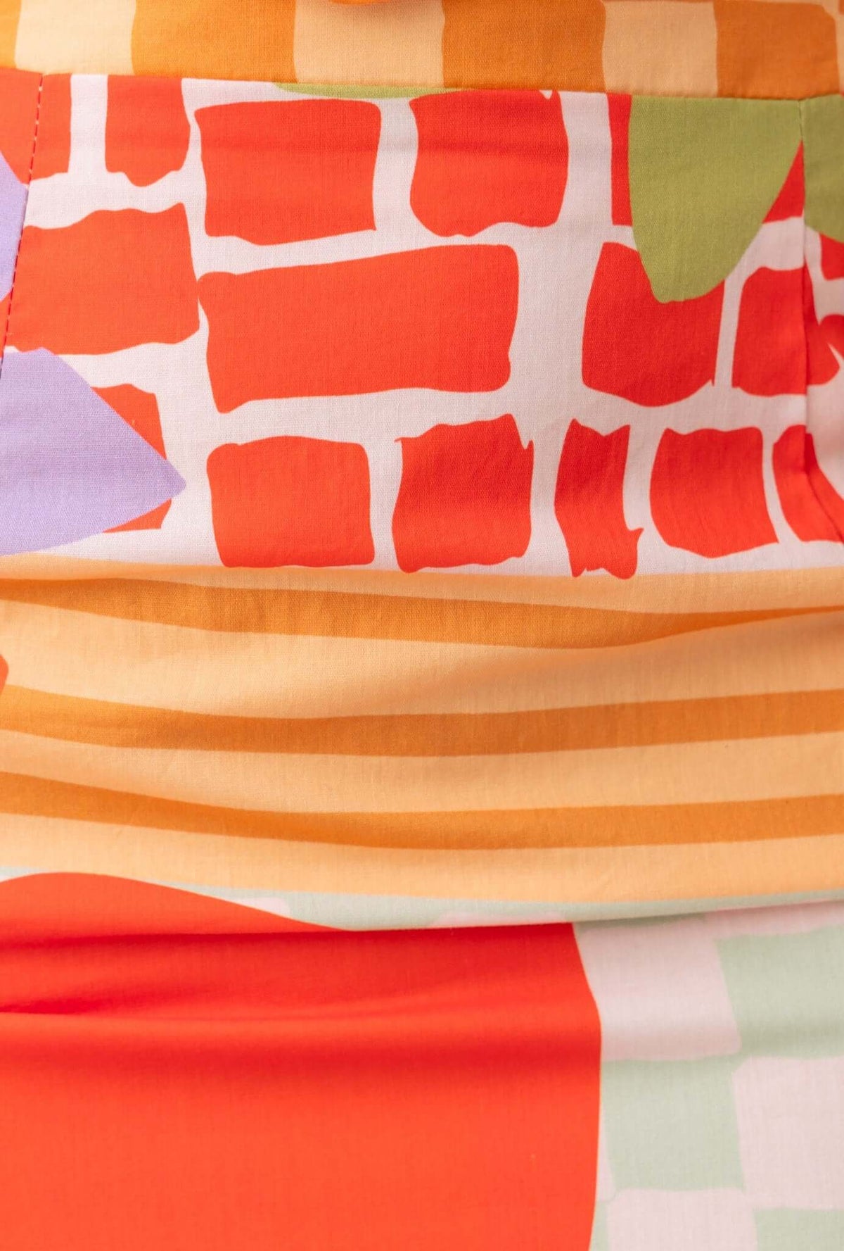 Close-up of colorful floral and patterned fabric showcasing vibrant orange and pastel tones.