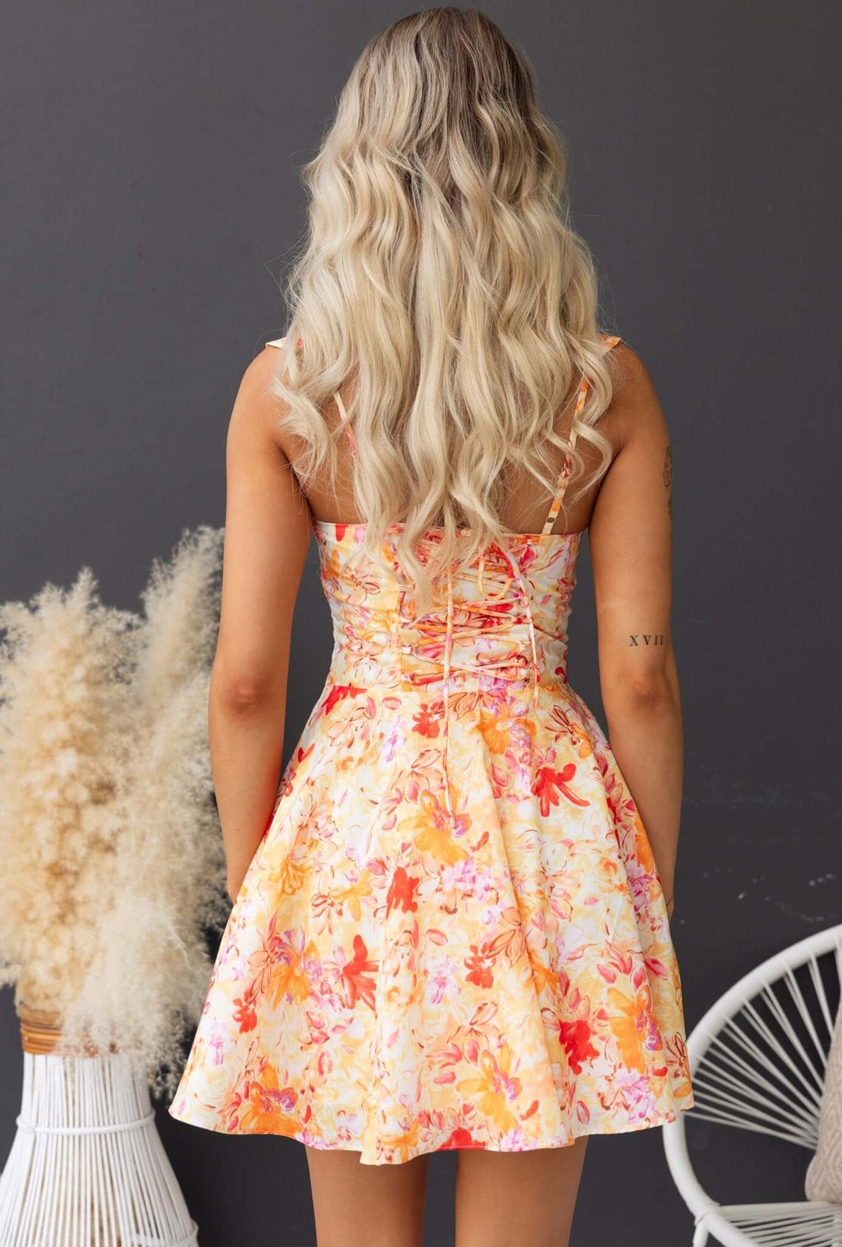 Back view of Elixir Dress featuring floral print, adjustable straps, and flared skirt.