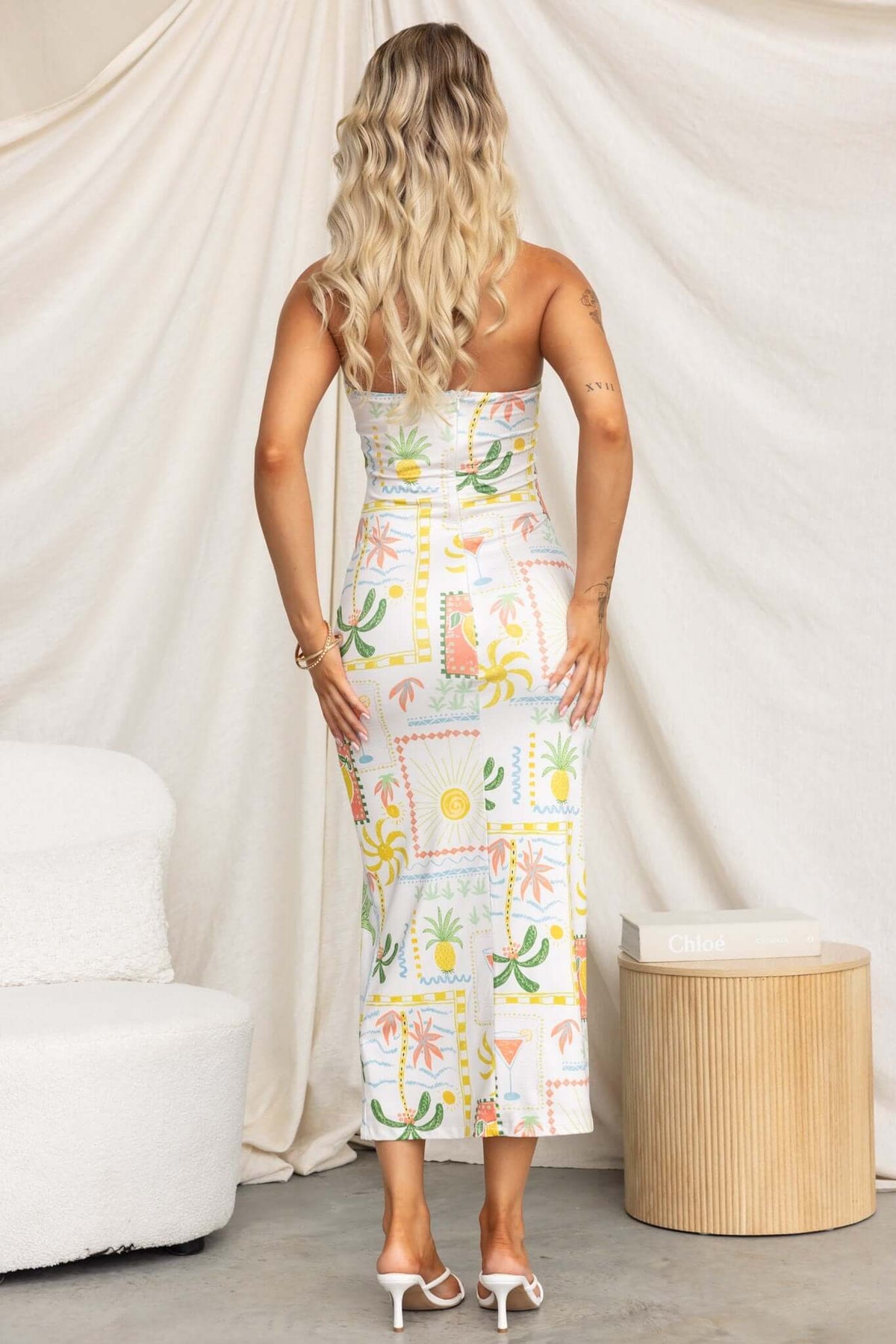 Back view of a model in a strapless Carianne Midi Dress with colorful tropical print, showcasing a fitted silhouette.