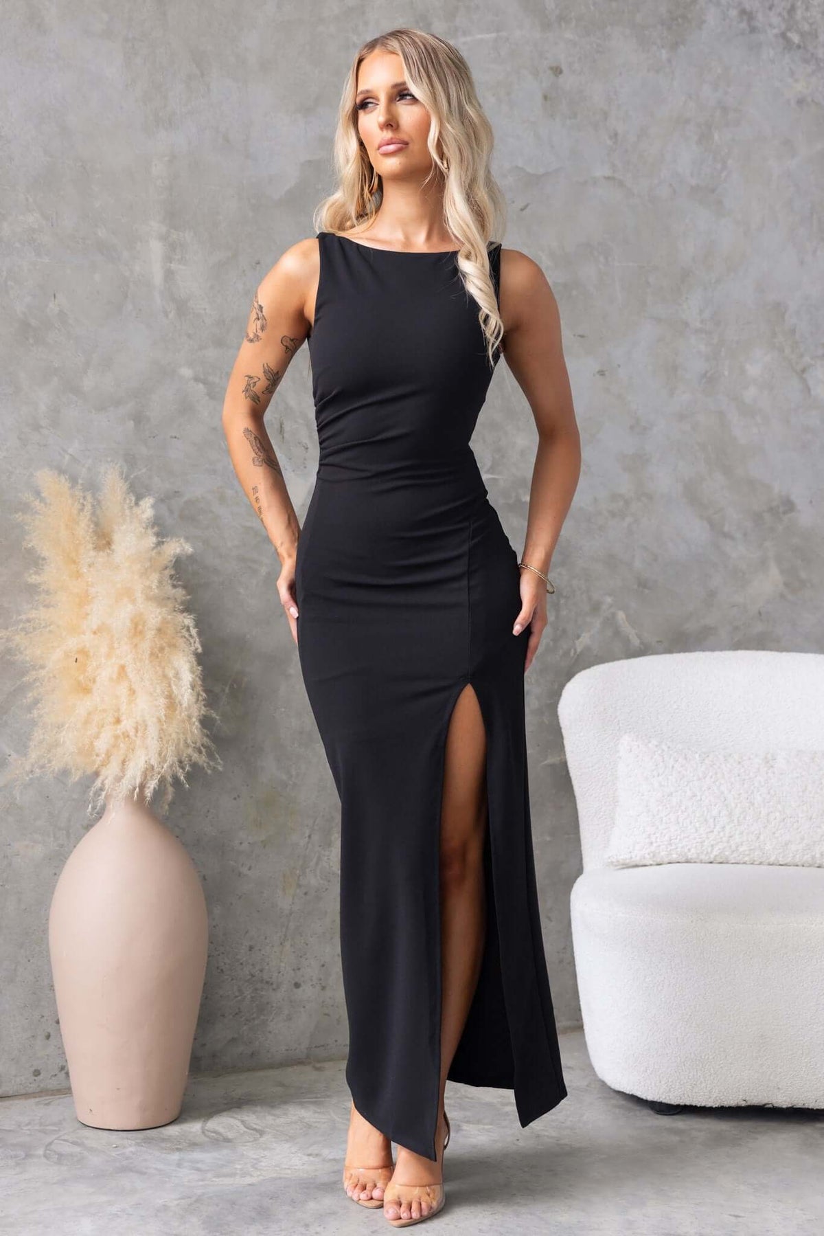 Model wearing a black Jarina Maxi Dress with high neckline and front split, styled against a minimalist background.