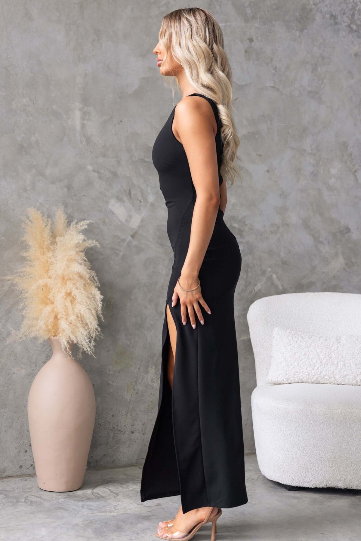 Side view of a woman in a black Jarina Maxi Dress with a high neckline and front split.