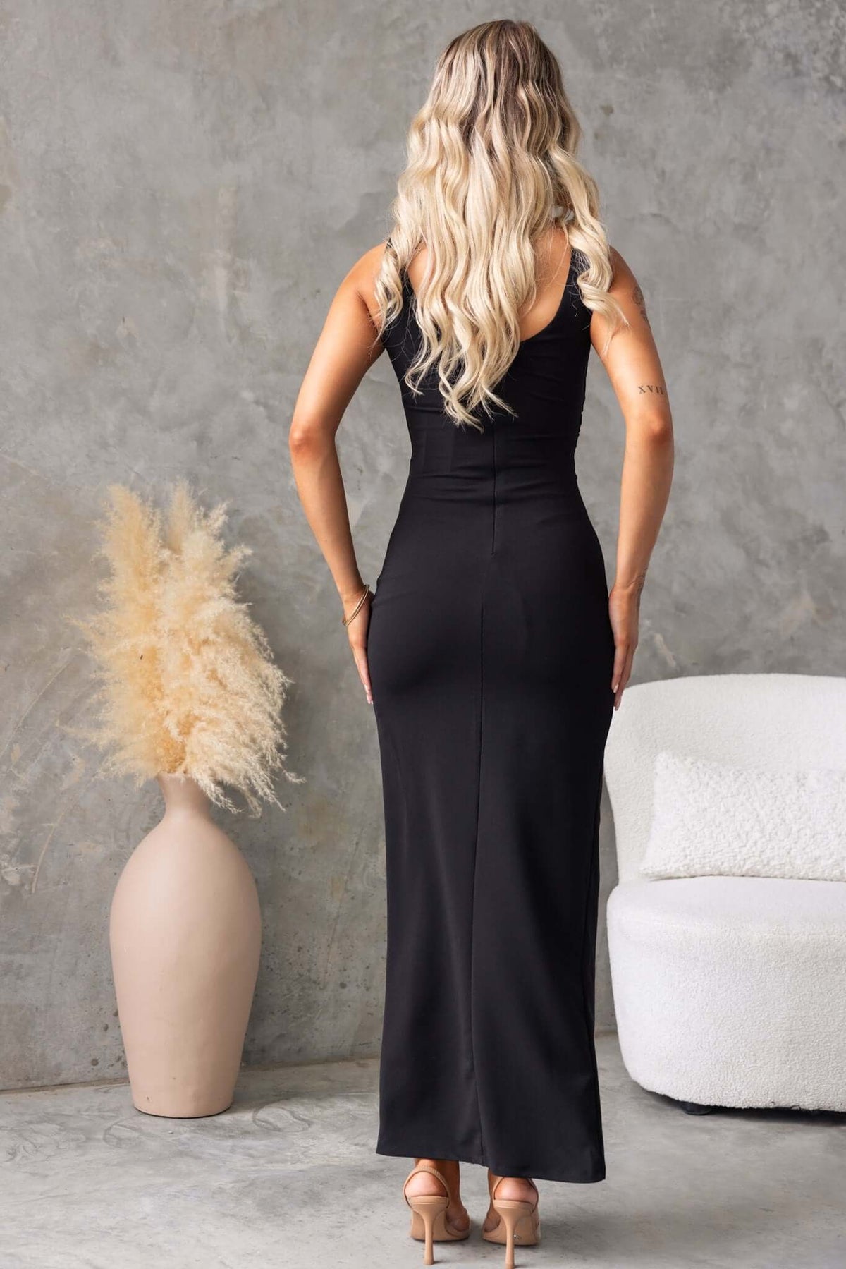 Model wearing the Jarina maxi dress from the back, showcasing its sleek design and high neckline.