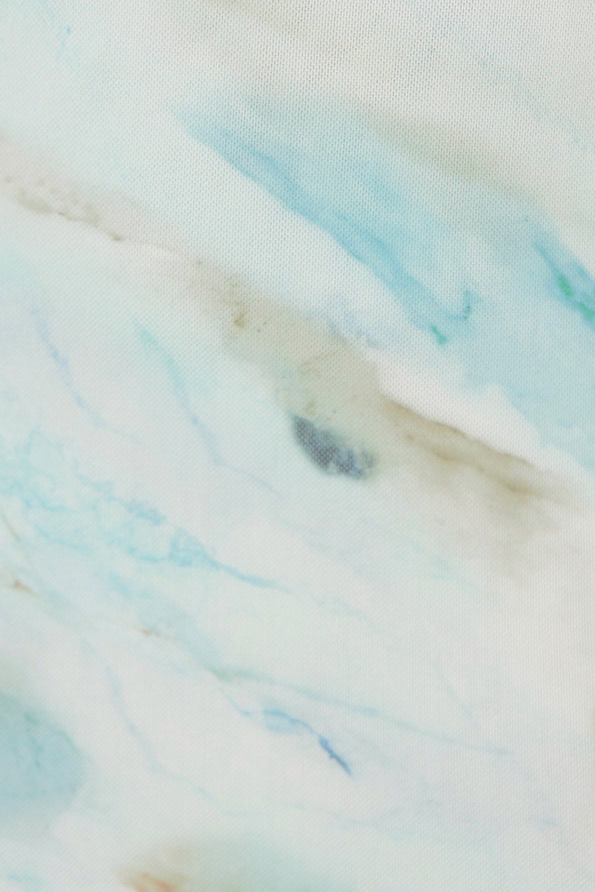 Close-up of abstract fabric in soft blue and cream tones, showcasing a marbled design perfect for a stylish maxi dress.