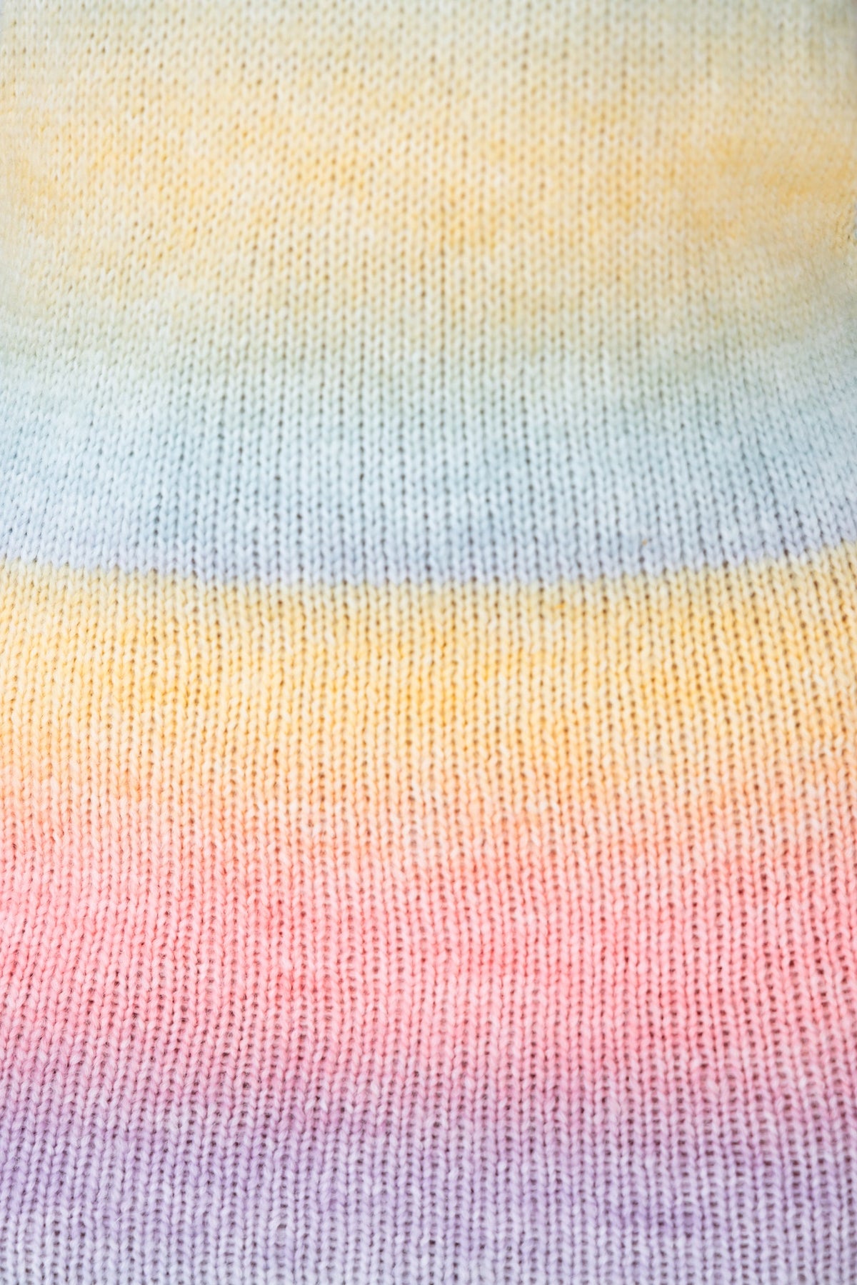 Close-up of soft knit fabric in pastel rainbow colors, featuring shades of yellow, blue, pink, and lavender.