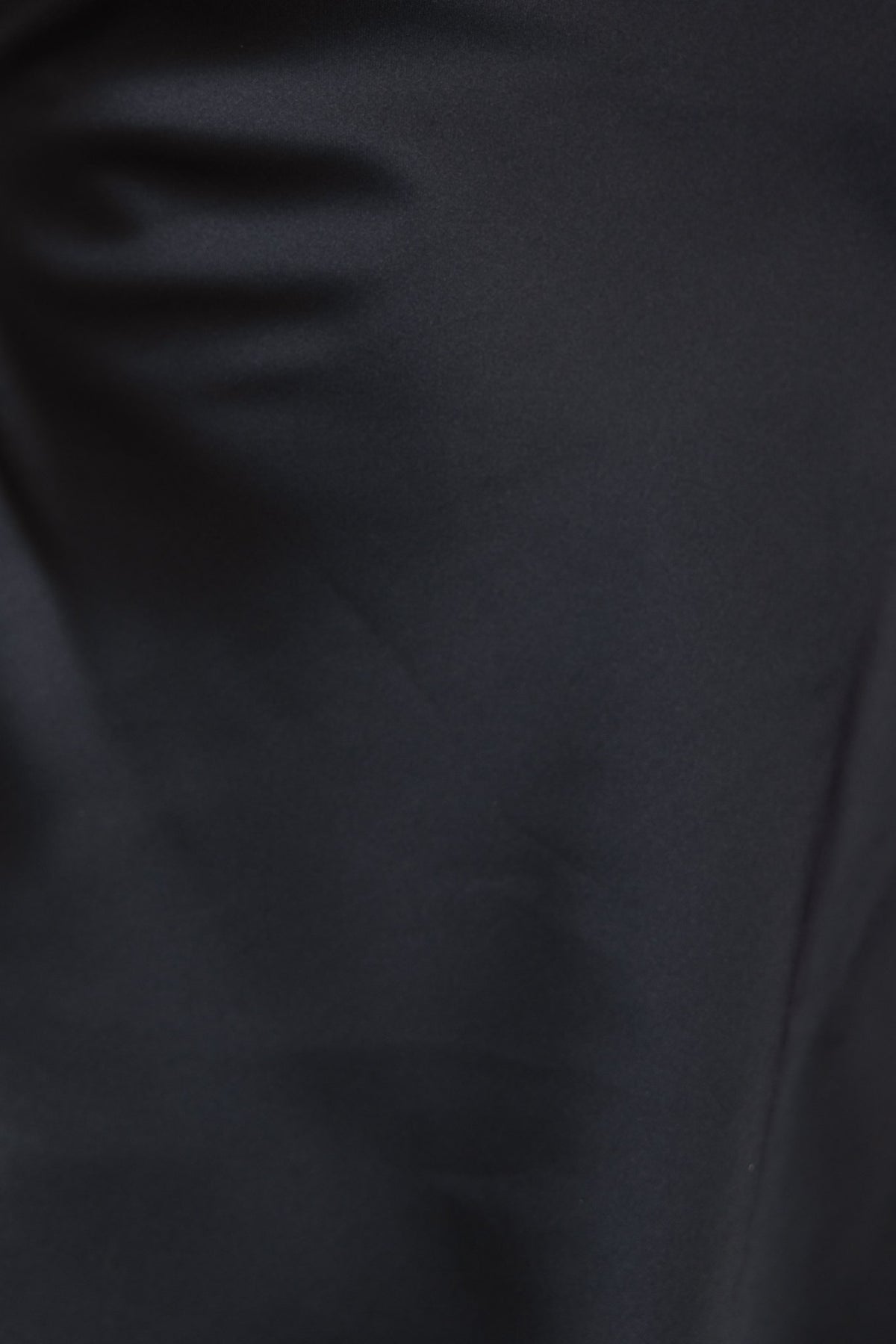 Close-up of black satin fabric showcasing smooth texture, ideal for Amore Pants with a mid-high waist and flare leg.