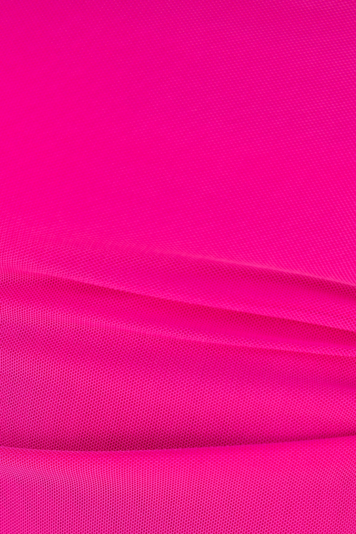 Close-up of vibrant pink mesh fabric showcasing its smooth texture and draping suitability for stylish designs.