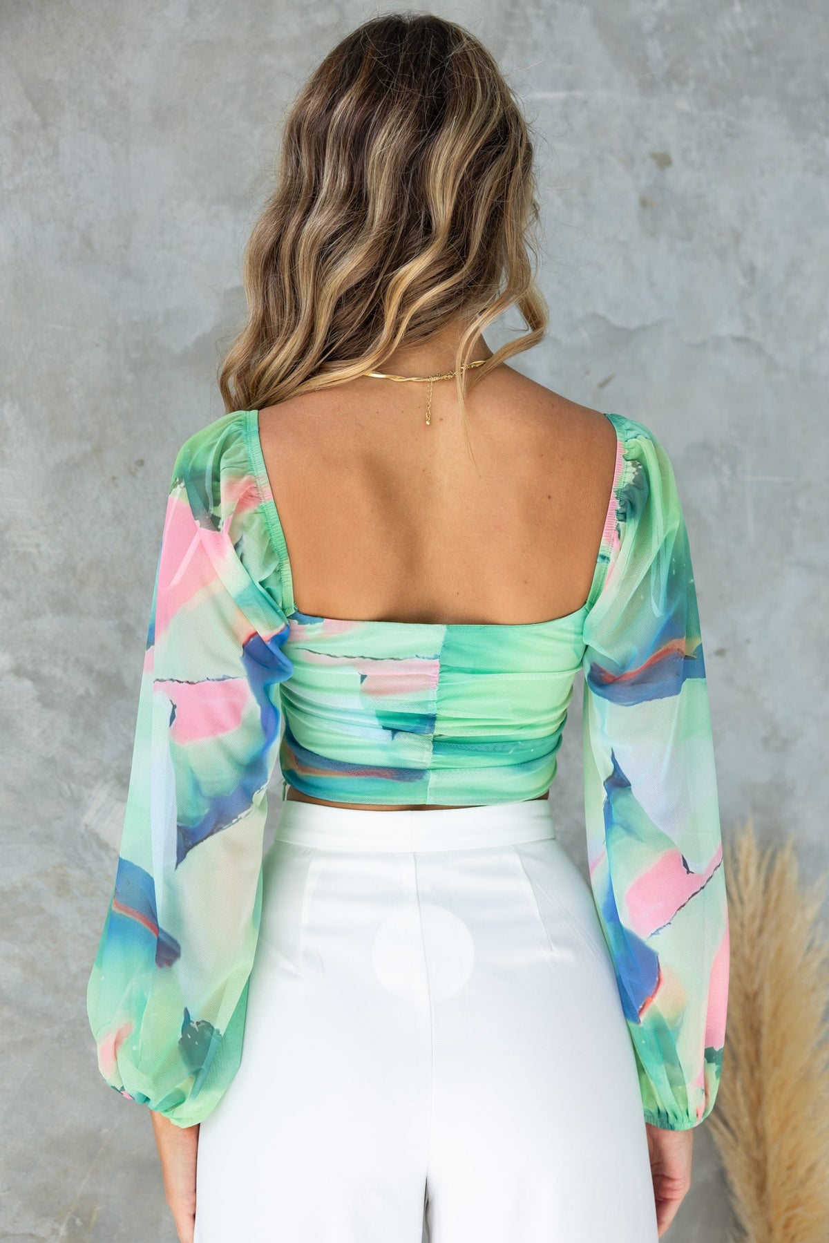 Back view of Caprice Top featuring multi-colour print, elastic sleeves, and twist bust detail.