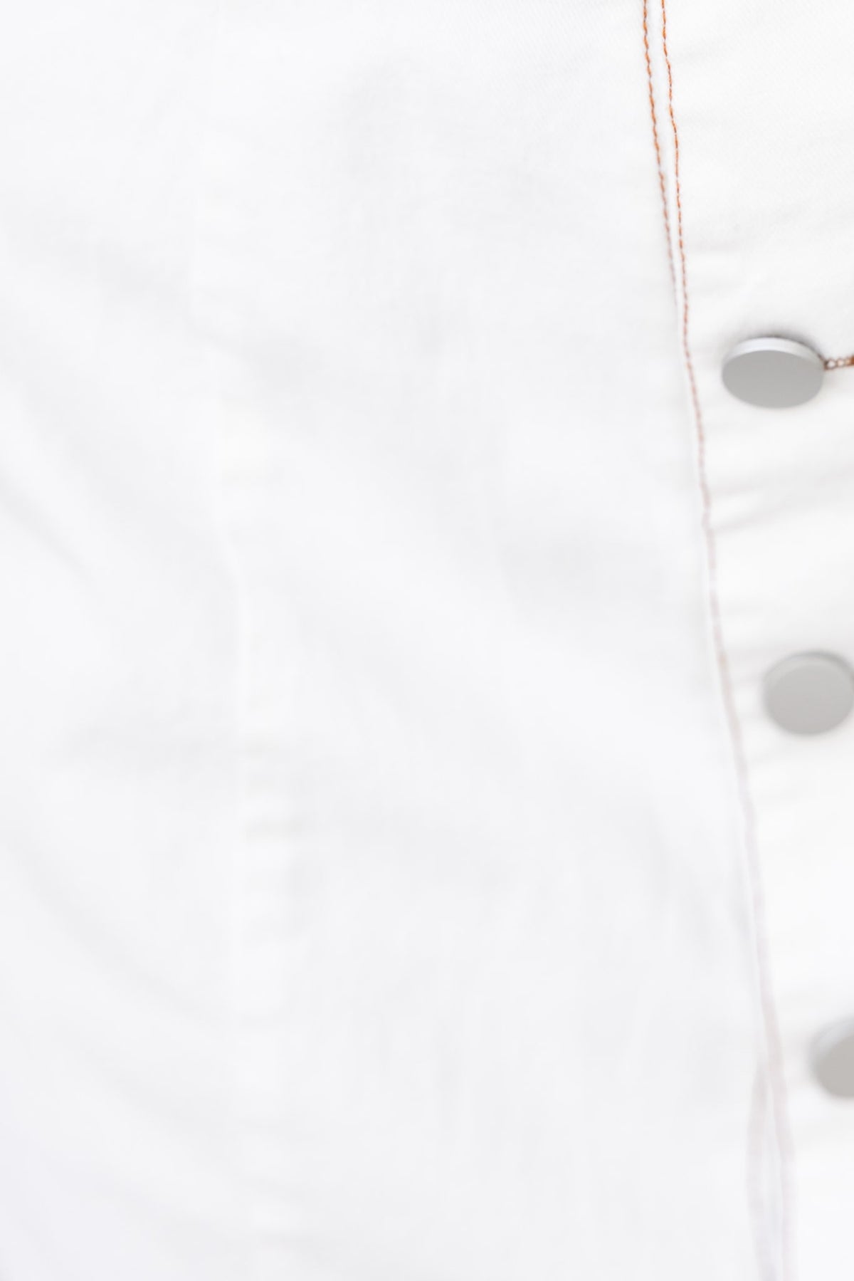 Close-up of button detail on white fabric showcasing sewing and texture.
