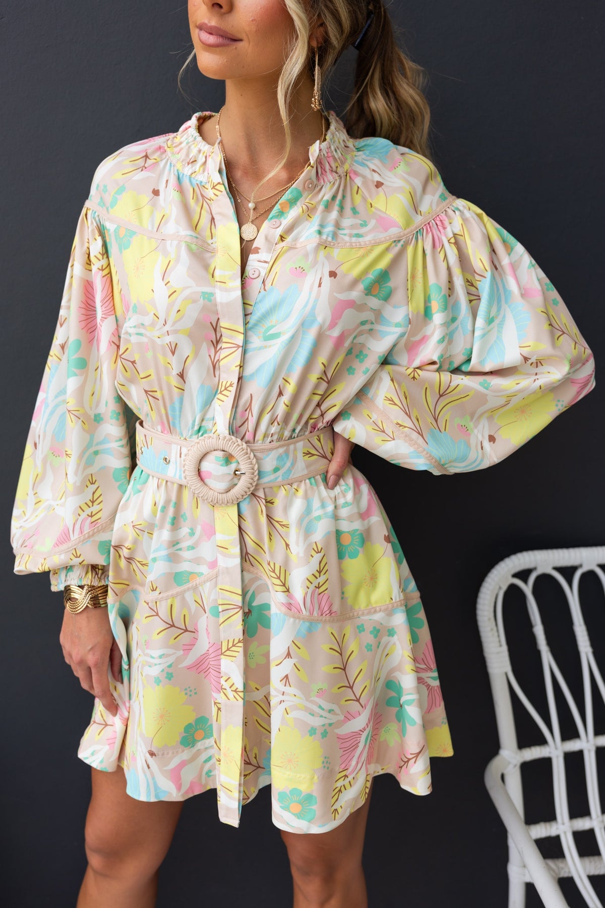 Model wearing Antonia Dress with elastic neckline, removable belt, and floral print in pastel colors.