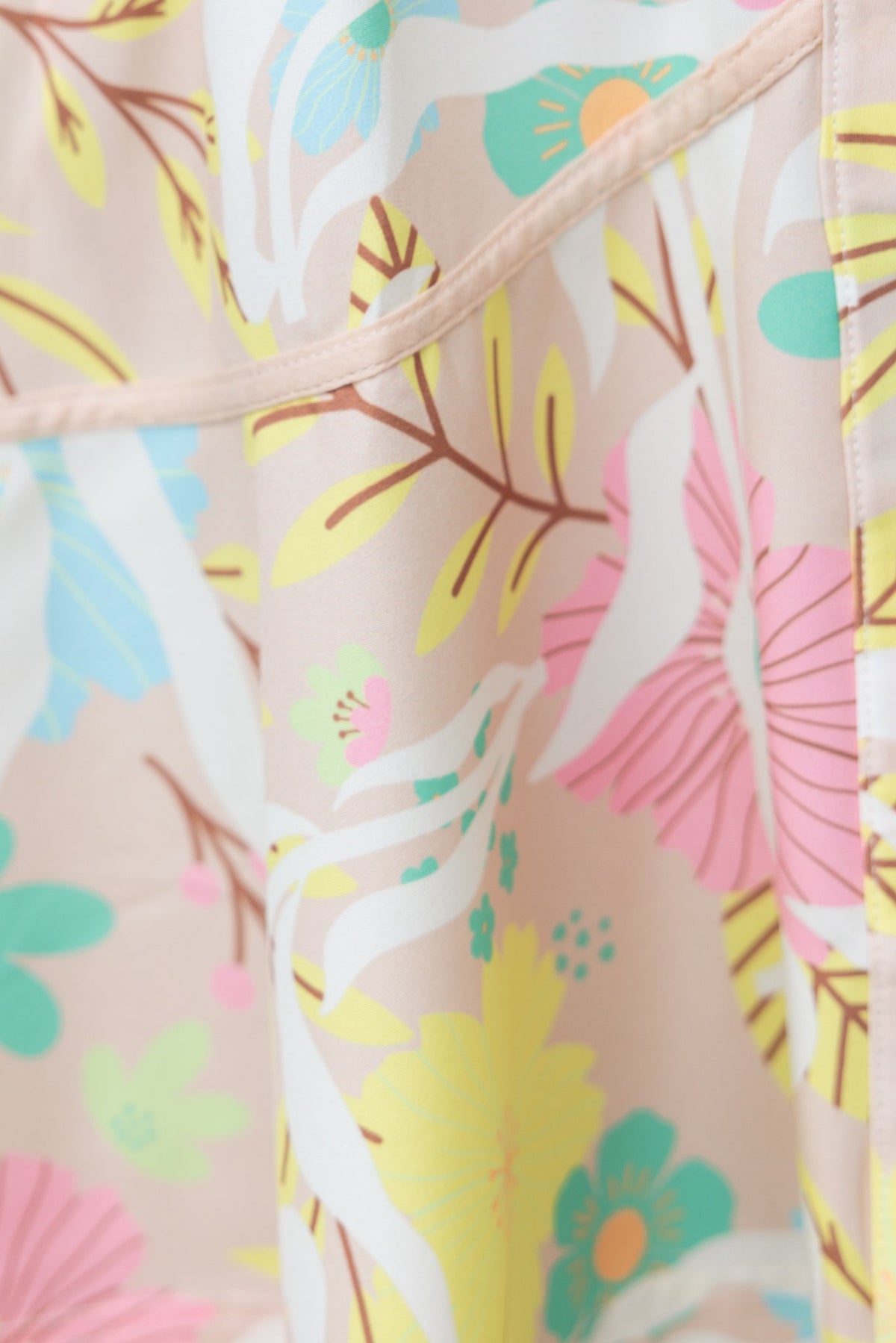 Close-up of floral pattern on Antonia Dress featuring vibrant colors like pink, yellow, and green on a soft background.