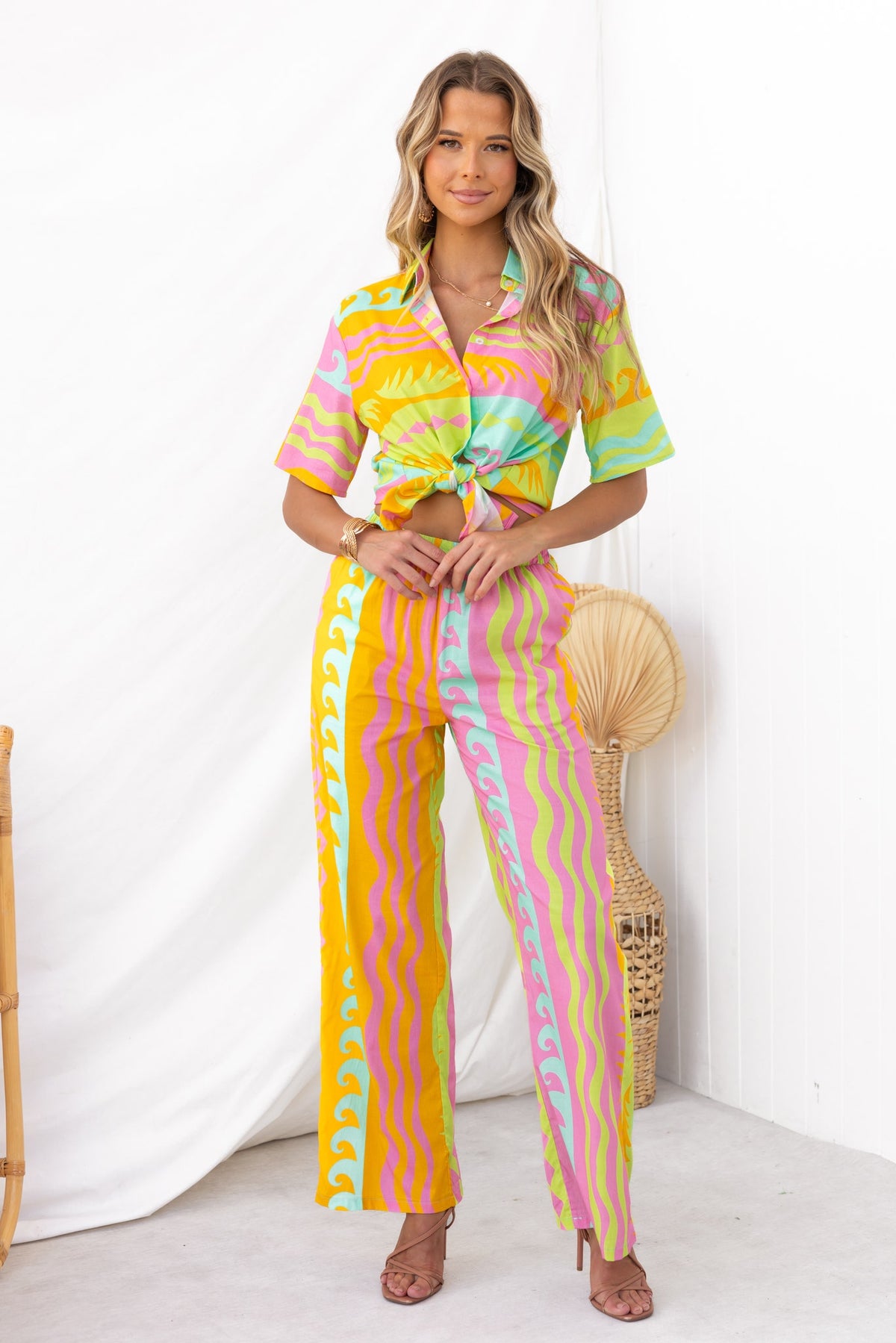 Model wearing a colorful Verney Shirt with patterned pants, showcasing a vibrant summer look in a stylish setting.
