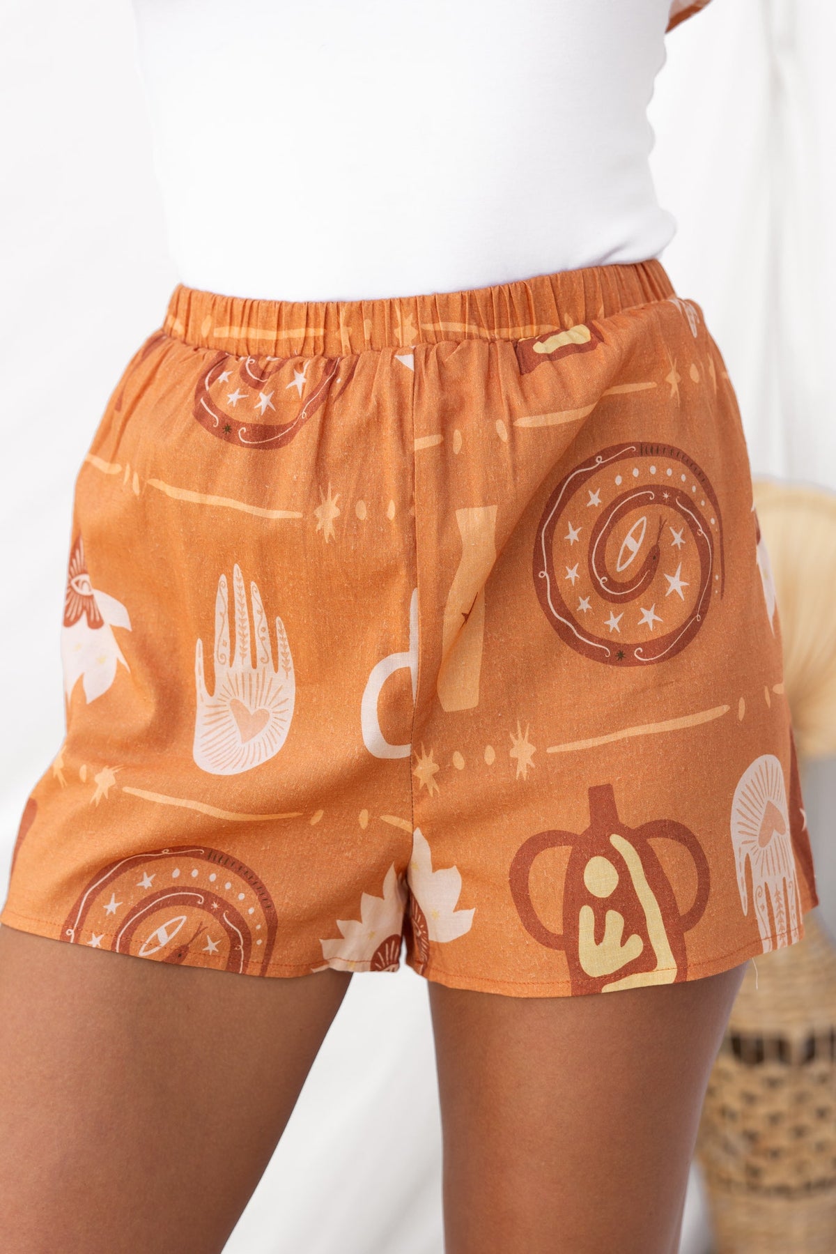 Stylish orange shorts with unique hand and geometric patterns, featuring an elastic waistband for comfort.