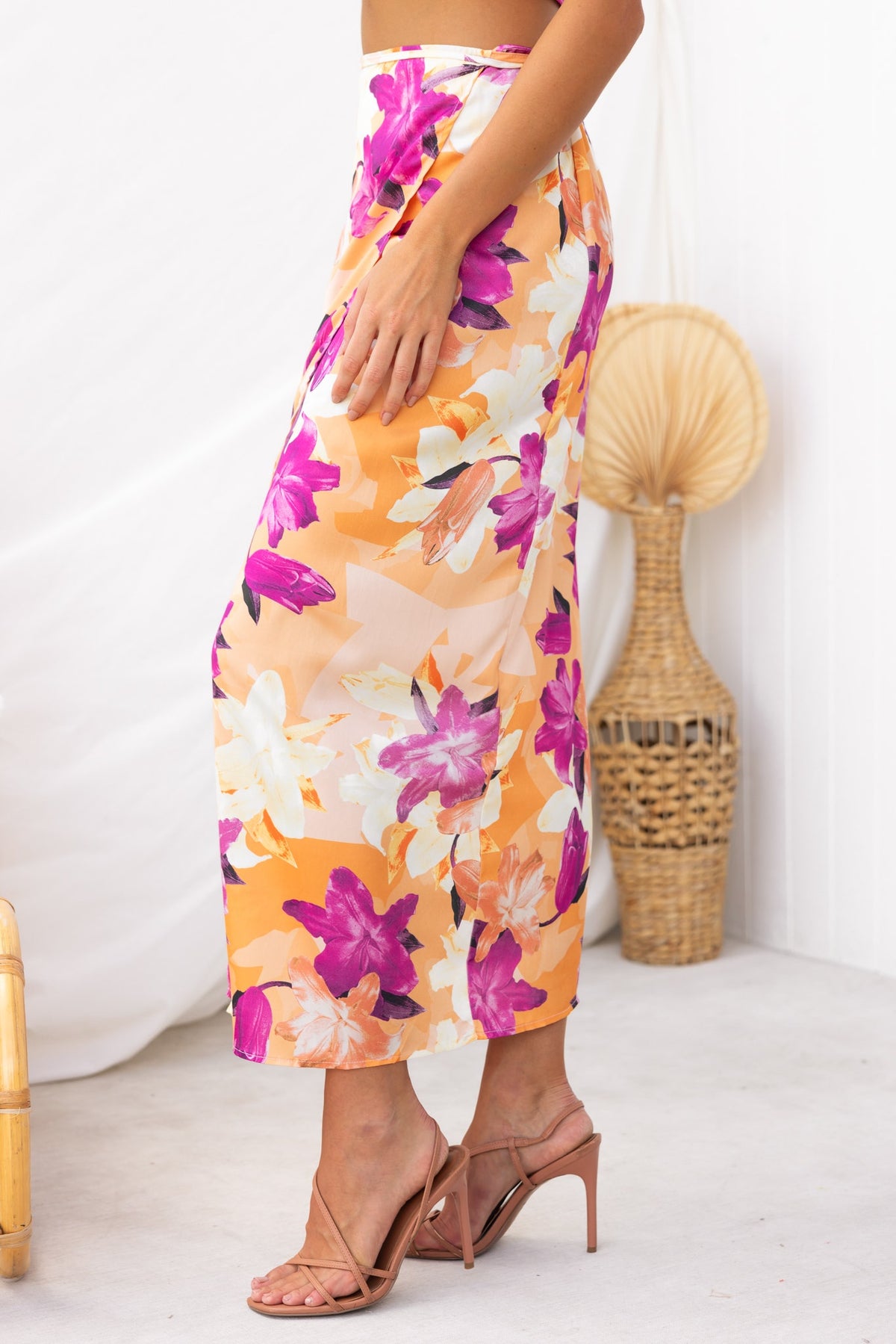 Nerida Wrap Midi Skirt with floral design in orange, pink, and white, featuring a side tie and asymmetric hem.