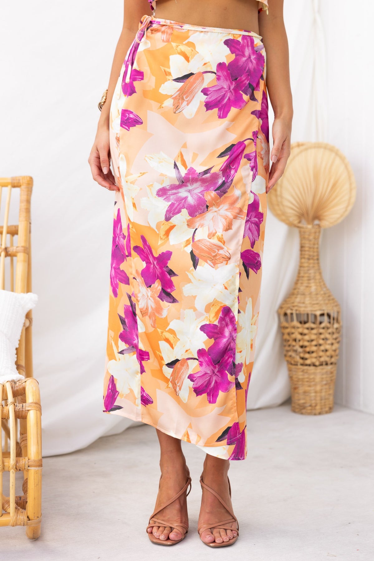 Nerida Wrap Midi Skirt featuring a floral design in vibrant pink and orange hues, with an asymmetric hem and satin finish.