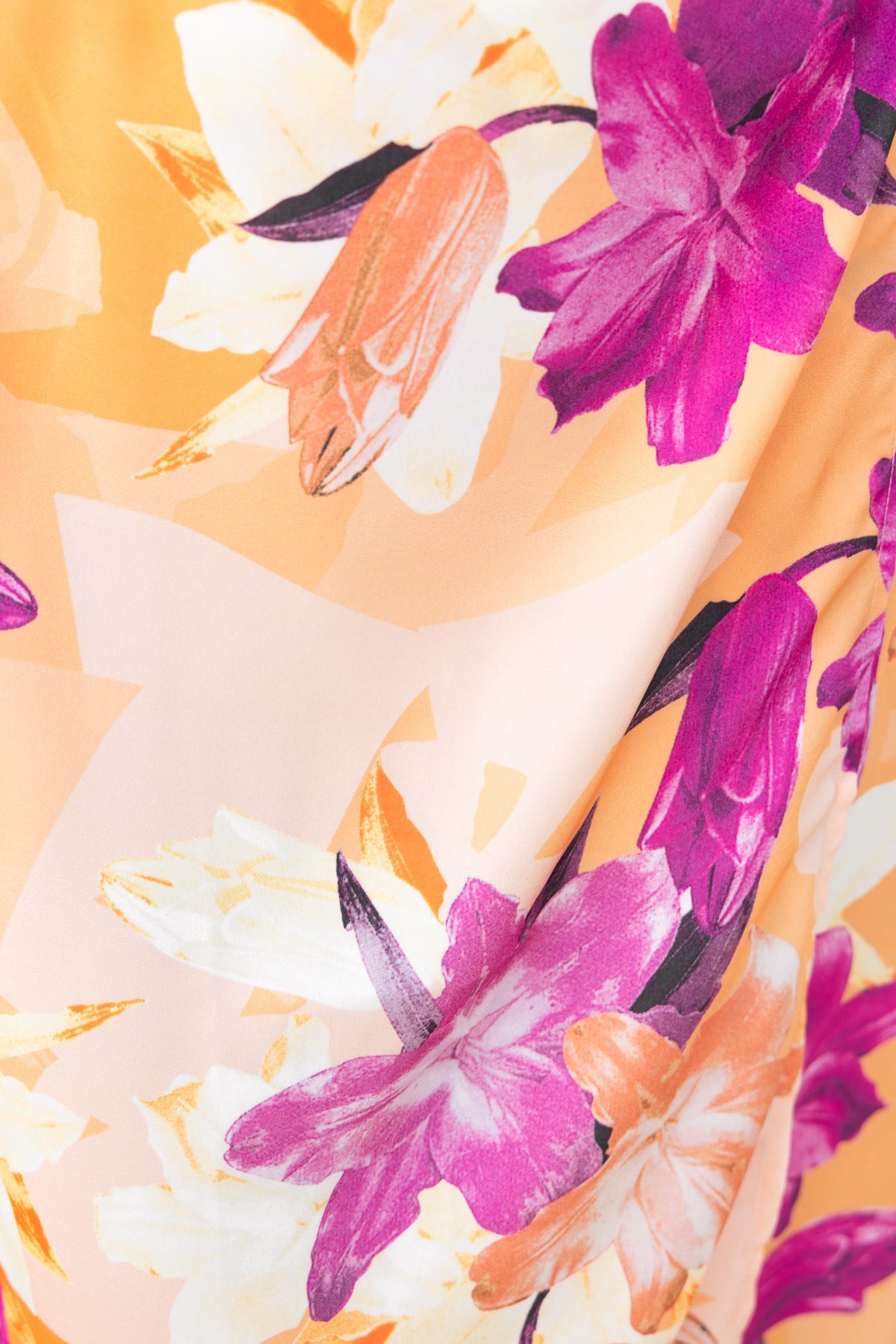 Close-up of colorful floral print featuring purple and orange flowers on a satin fabric.