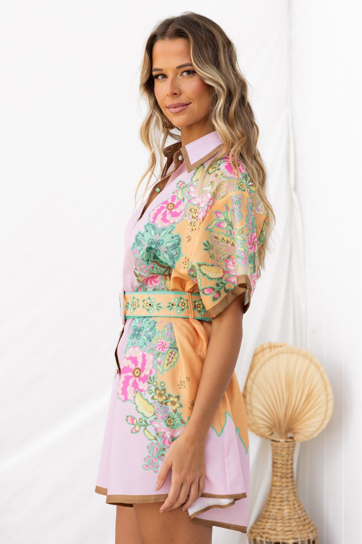Model wearing the Jaziel Dress, a colorful button-up dress with a floral design and removable belt.