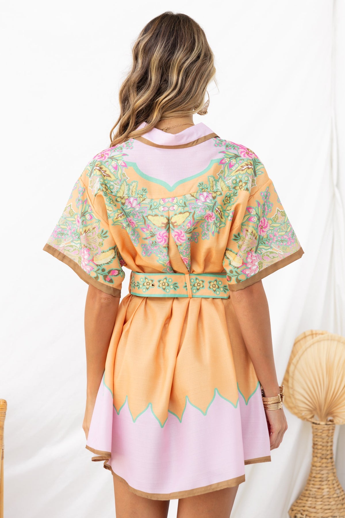 Back view of the Jaziel Dress featuring floral embroidery, a removable fabric belt, and a relaxed fit in pastel colors.