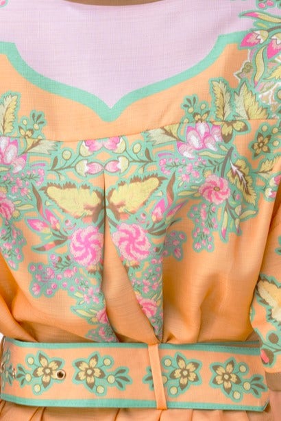 Close-up of Jaziel Dress featuring vibrant floral patterns and a removable belt in orange and green shades.