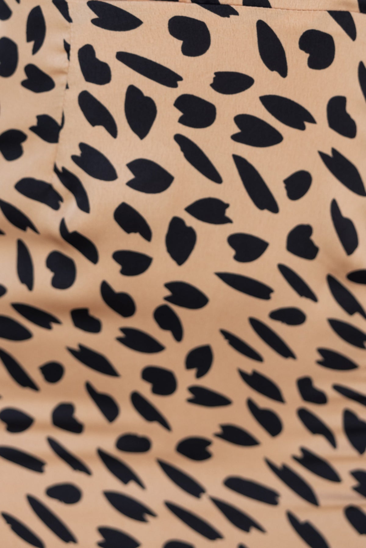Close-up of a beige fabric featuring a trendy black heart print, perfect for stylish garments like dresses.