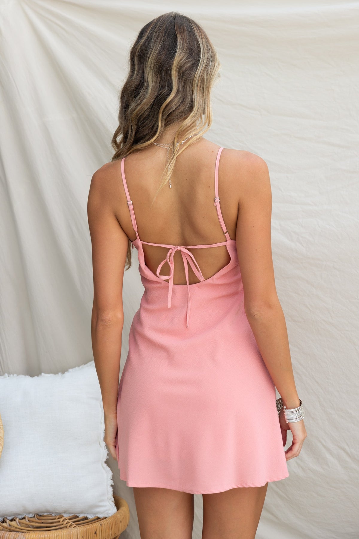 Back view of a woman in a pink Zhuri Dress with adjustable straps and a tie detail.