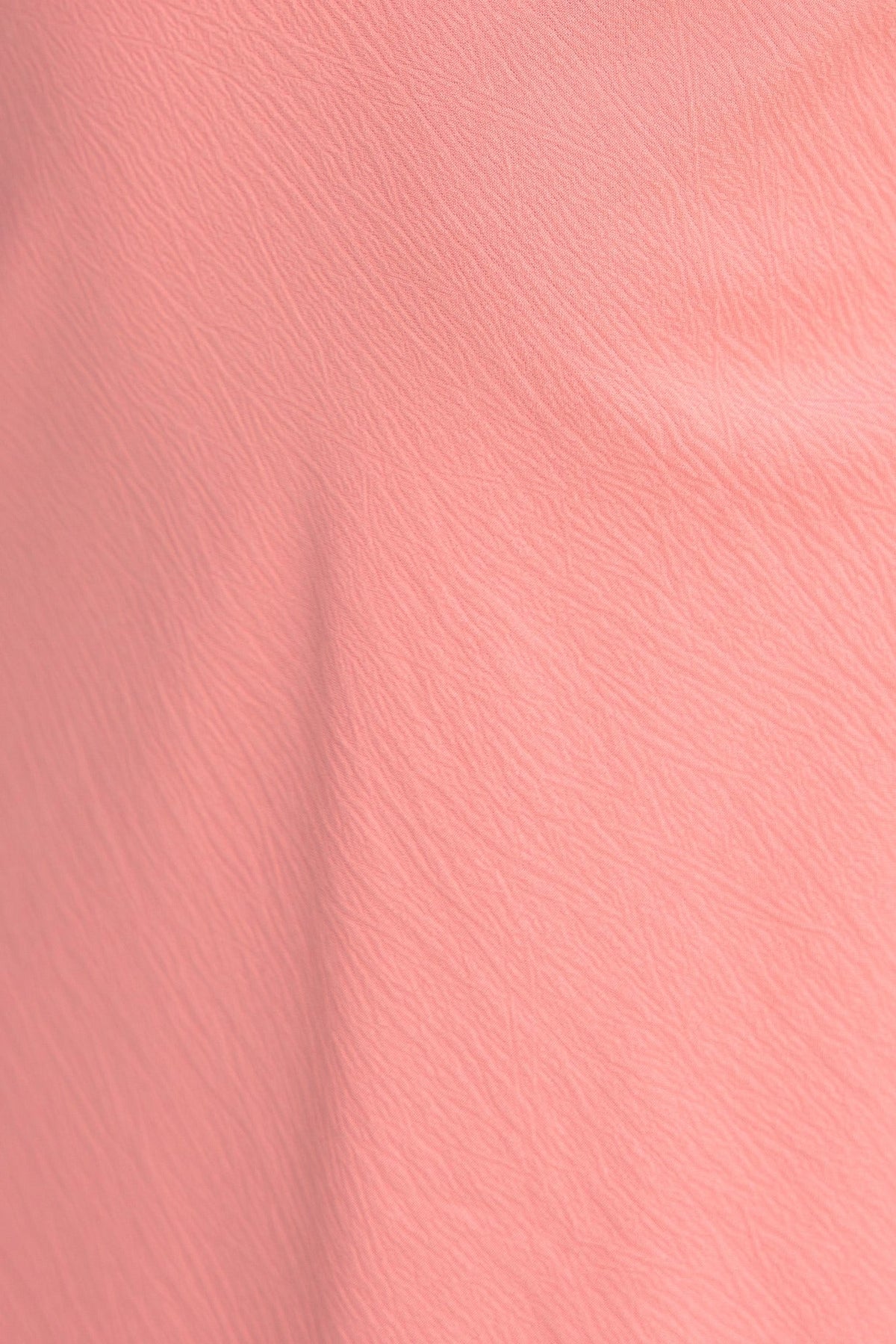 Close-up of textured peach fabric from the Zhuri Dress, showcasing its soft material and unique finish.
