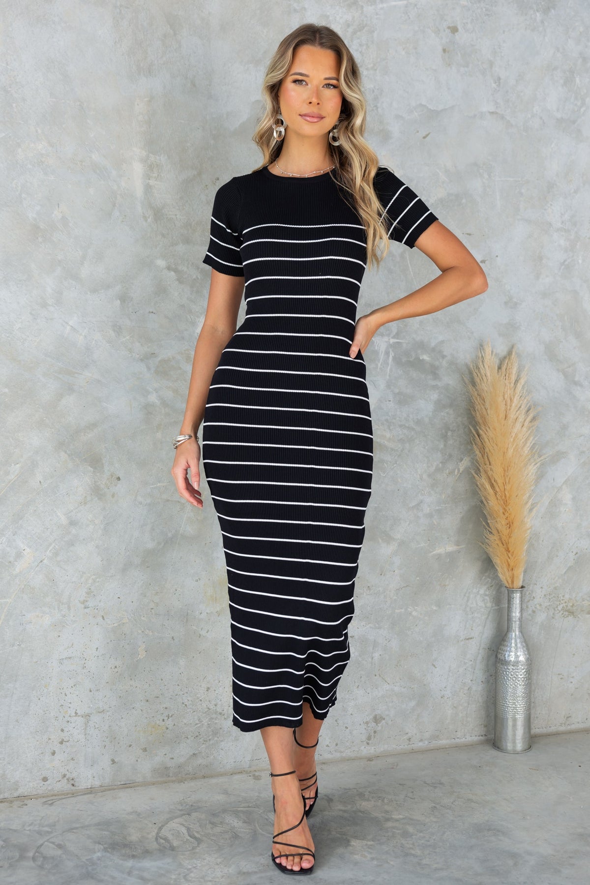 Woman wearing a black striped Siann midi dress with a round neckline and fitted silhouette.