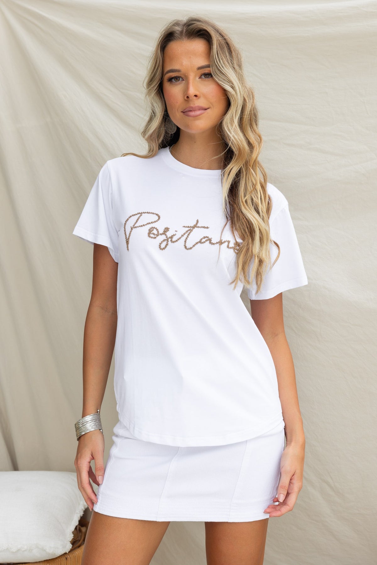 Model wearing the Landon Tee, a white cotton shirt featuring 'Positano' print and a round neckline.