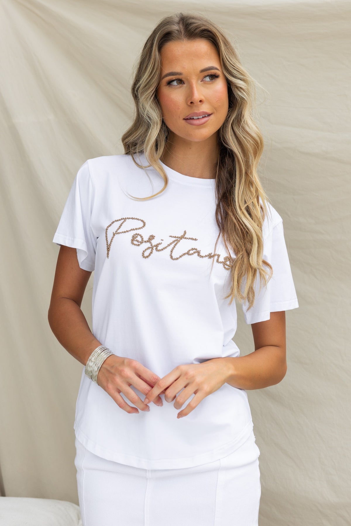Model wearing white Positano print tee with round neckline and bead detail, showcasing a light soft cotton feel.