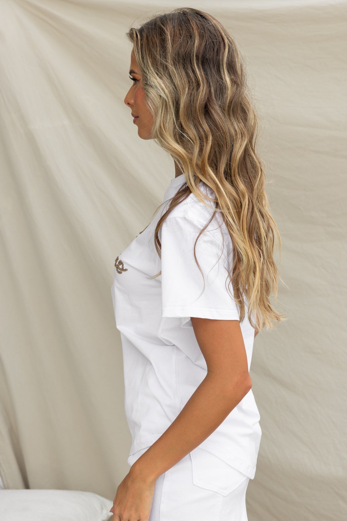 Model showcasing the Landon Tee, featuring a round neckline, soft cotton, and bead detail in a white design.