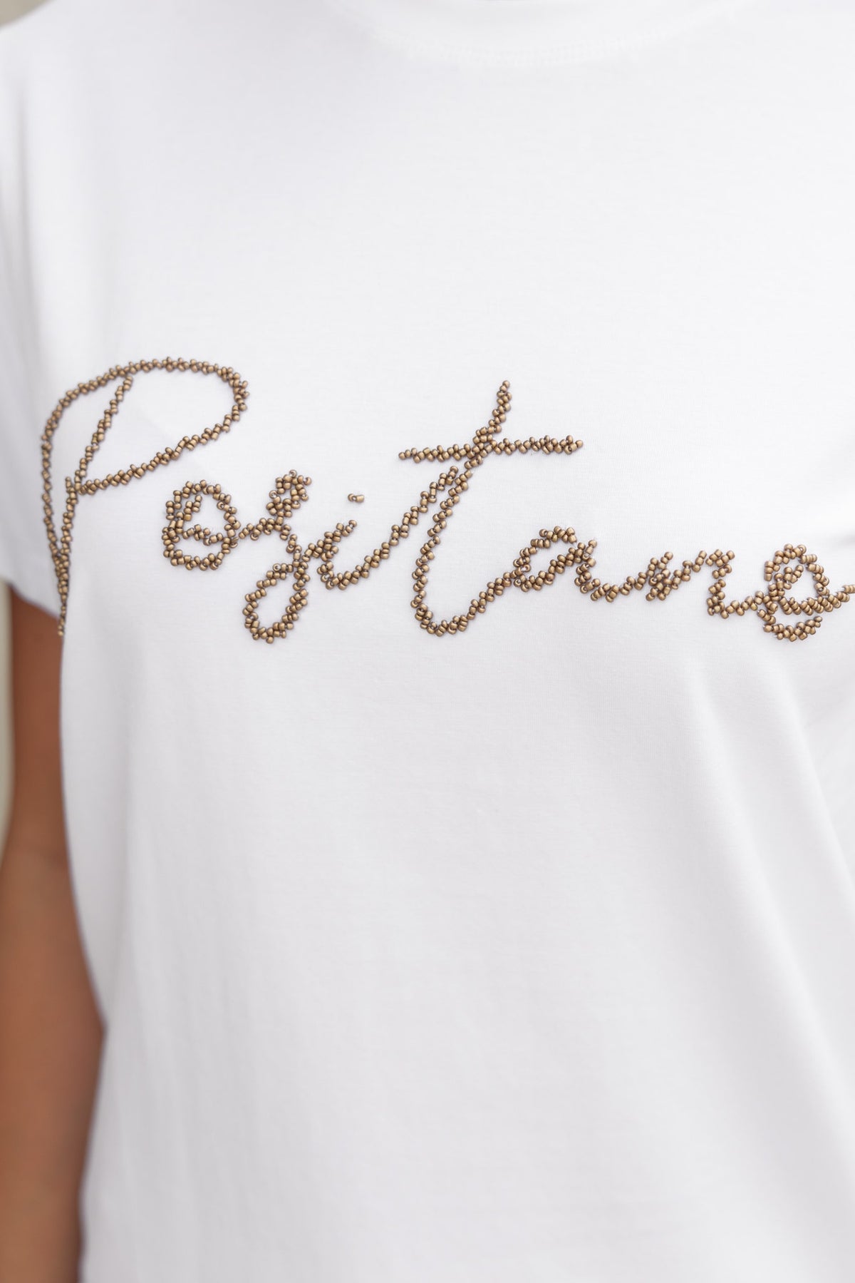 Landon Tee white cotton shirt featuring "Positano" bead detail on the front, showcasing soft material and stretch.