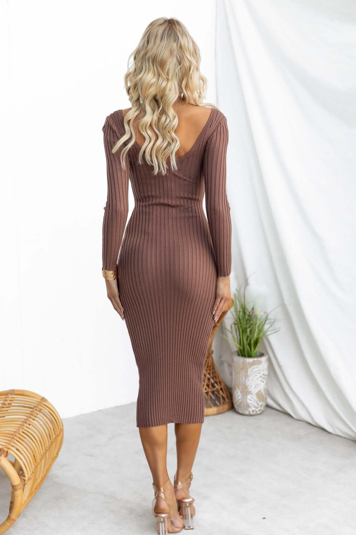 Back view of a woman wearing a brown ribbed Aquino Midi Dress with a V-neckline and long sleeves.