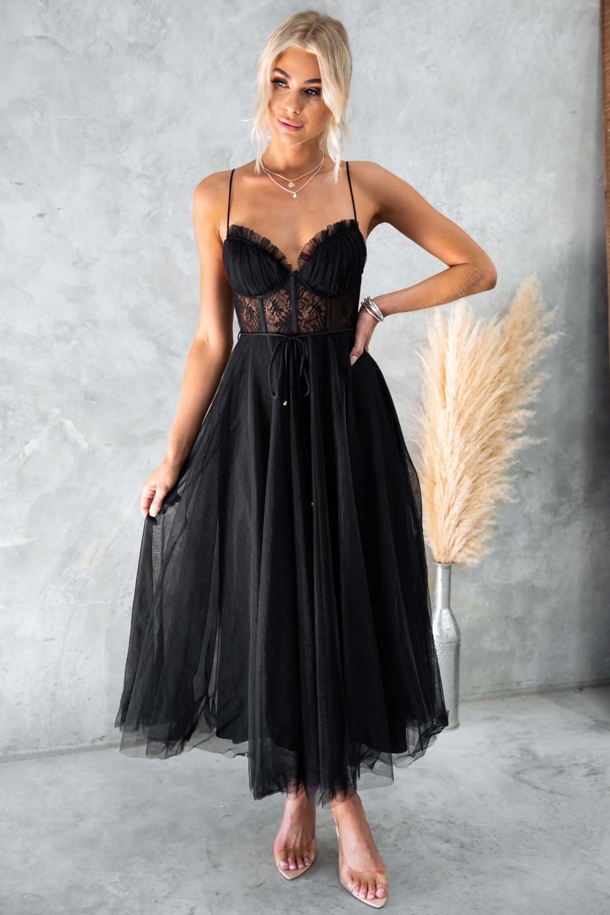 Model wearing a black tulle maxi dress with adjustable straps and lace detail, perfect for summer occasions.
