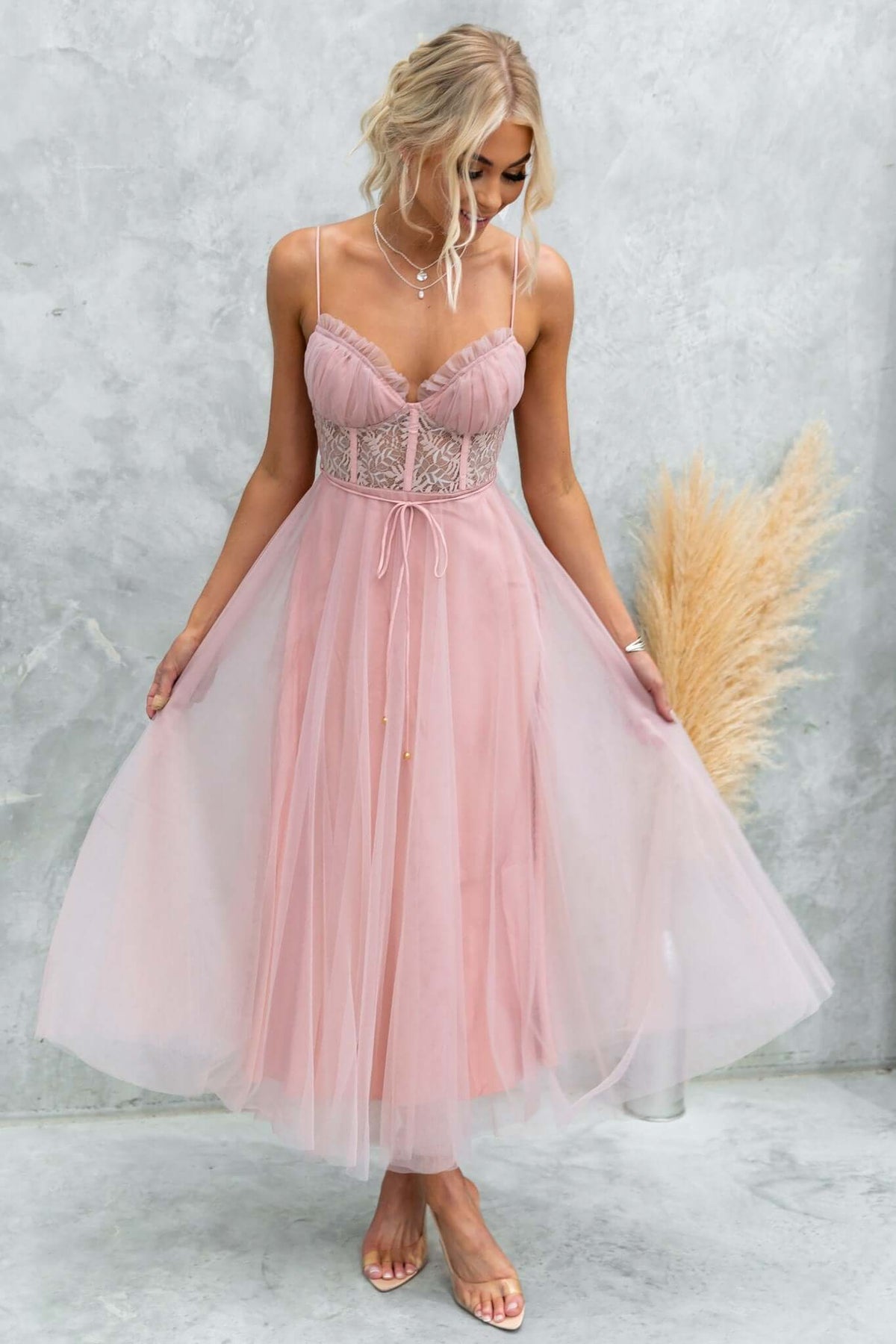 Model wearing a pink Wash Away Maxi Dress with tulle skirt and lace detail, showcasing adjustable straps and removable tie.